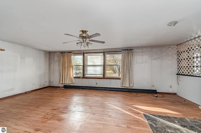 unfurnished room featuring ceiling fan, light hardwood / wood-style flooring, and a baseboard heating unit