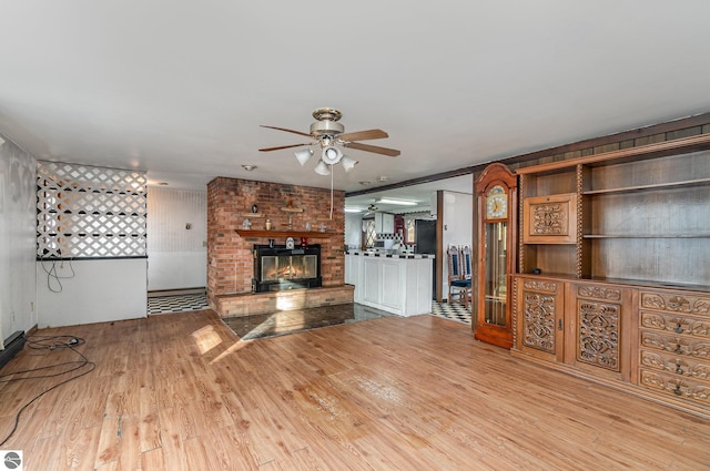 unfurnished living room featuring ceiling fan, light wood-type flooring, and a fireplace