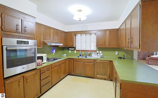 kitchen with a textured ceiling, sink, kitchen peninsula, and stainless steel appliances