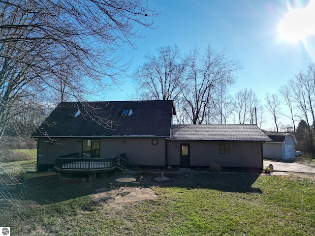 back of property featuring a yard, a deck, a garage, and an outdoor structure