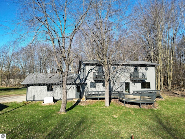 back of property featuring a balcony and a yard