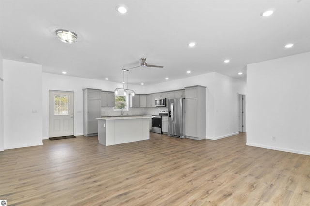 kitchen with gray cabinets, light hardwood / wood-style flooring, a kitchen island, and appliances with stainless steel finishes