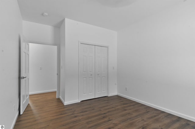 unfurnished bedroom with a closet and dark hardwood / wood-style flooring