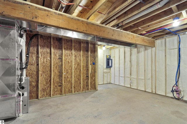 basement featuring electric panel and heating unit