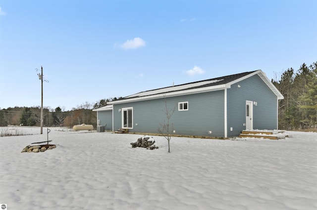 snow covered rear of property with central AC unit