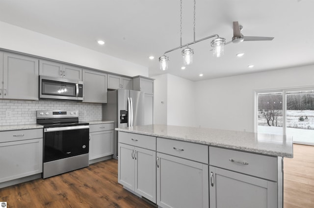 kitchen featuring ceiling fan, gray cabinets, light stone counters, appliances with stainless steel finishes, and dark hardwood / wood-style flooring