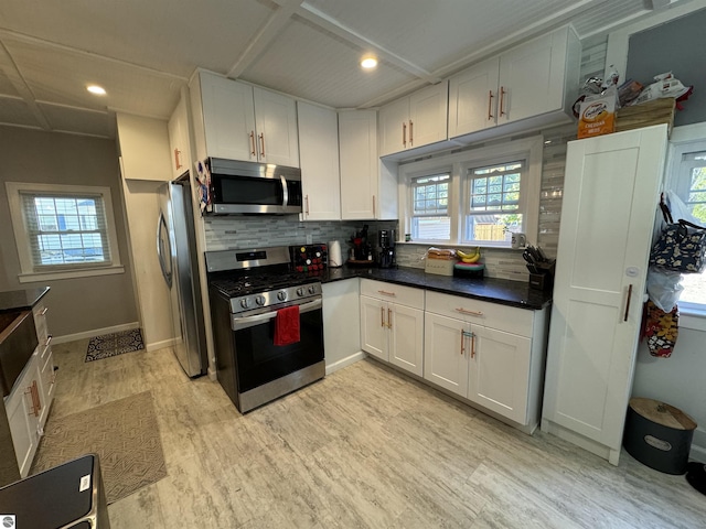 kitchen featuring tasteful backsplash, white cabinetry, stainless steel appliances, and light wood-type flooring