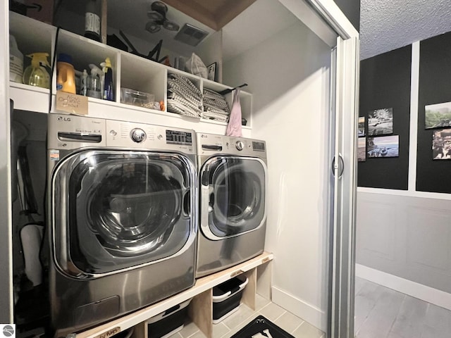 clothes washing area featuring tile patterned flooring, independent washer and dryer, and a textured ceiling