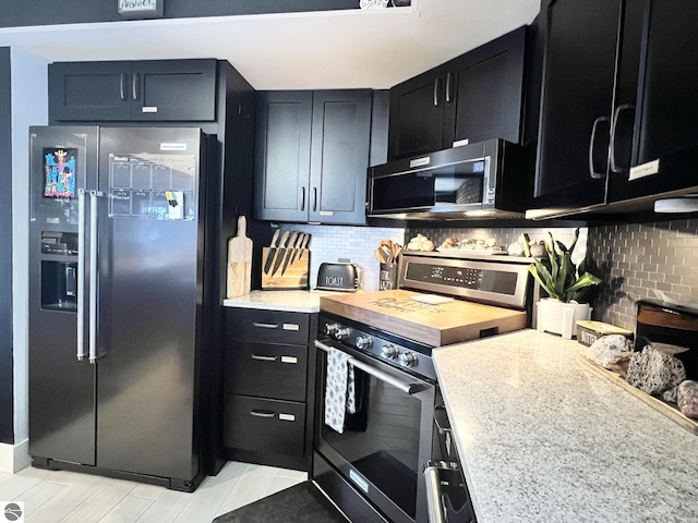 kitchen featuring butcher block countertops, light tile patterned floors, appliances with stainless steel finishes, and tasteful backsplash