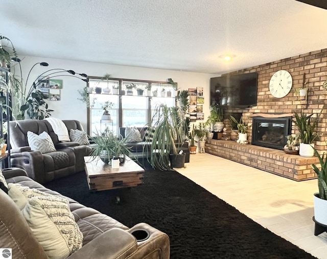 living room with wood-type flooring, a textured ceiling, and a brick fireplace