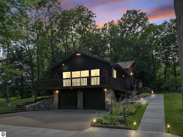 view of front facade featuring a yard, a garage, and a wooden deck