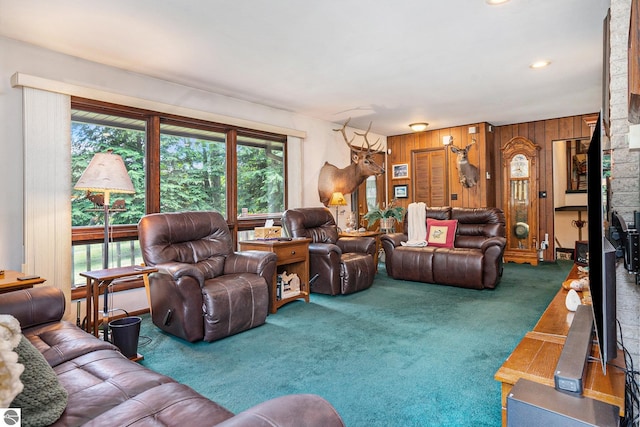 living room featuring carpet, a healthy amount of sunlight, and wooden walls