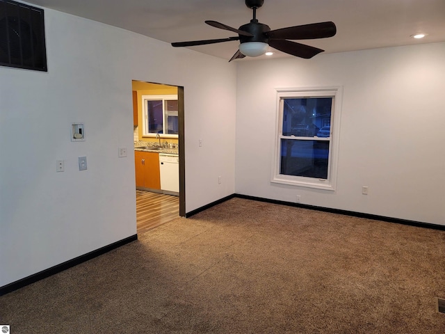 carpeted spare room featuring ceiling fan and sink