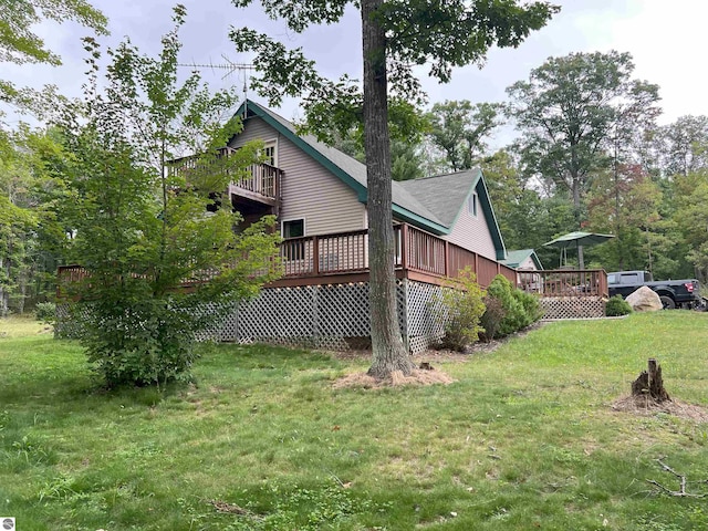 view of side of property featuring a wooden deck and a lawn