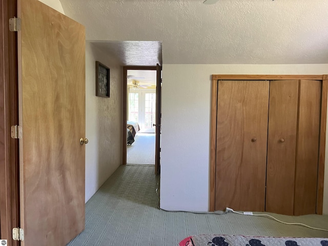 unfurnished bedroom with french doors, a textured ceiling, light carpet, and a closet