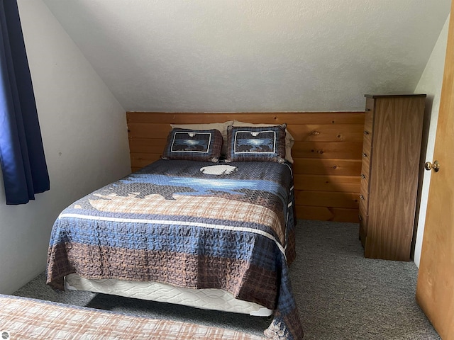 carpeted bedroom with a textured ceiling, wooden walls, and lofted ceiling