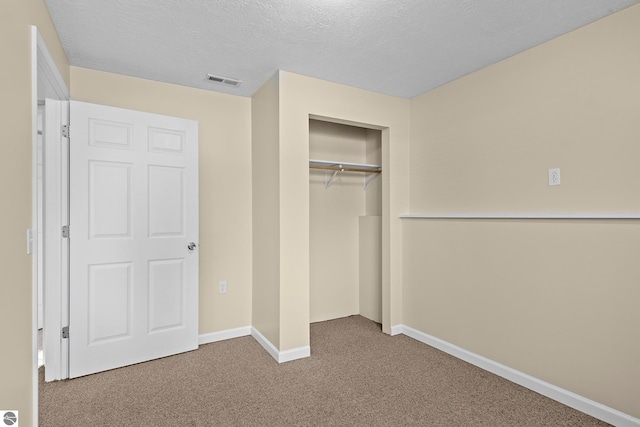 unfurnished bedroom featuring a textured ceiling, carpet floors, and a closet