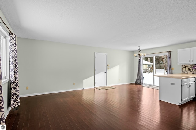 interior space featuring a textured ceiling, dark hardwood / wood-style flooring, and an inviting chandelier