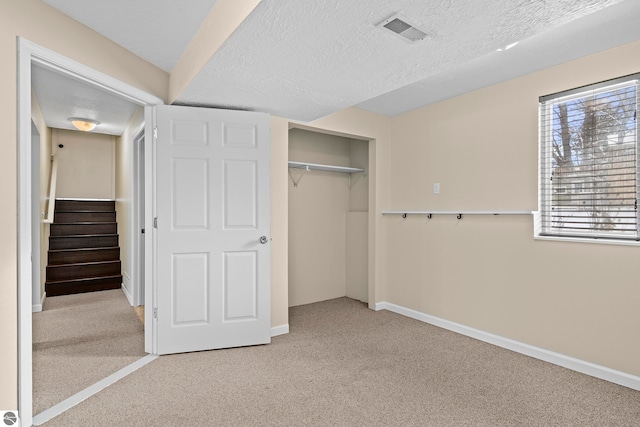 unfurnished bedroom featuring light colored carpet, a textured ceiling, and a closet