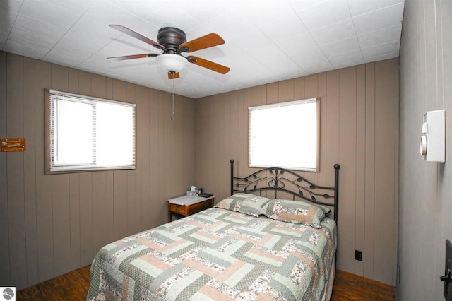 bedroom featuring wood walls, dark hardwood / wood-style floors, and ceiling fan