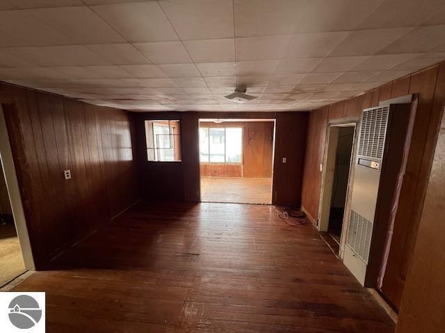 corridor featuring a paneled ceiling, hardwood / wood-style flooring, and wood walls