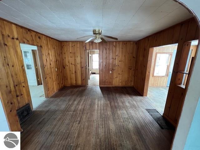 spare room with dark hardwood / wood-style flooring, ceiling fan, and wooden walls