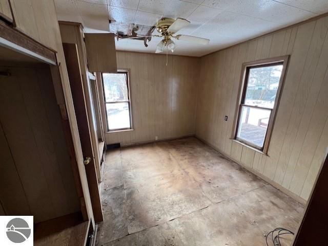 spare room featuring wooden walls and ceiling fan