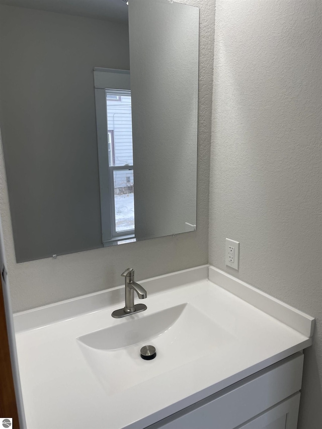 bathroom with a textured wall and vanity