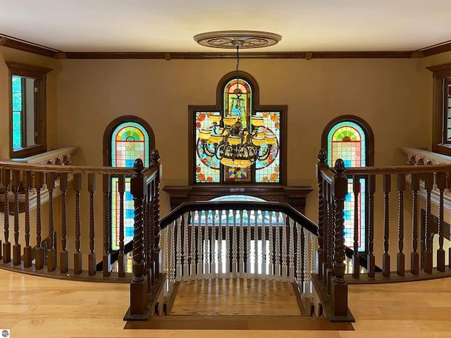 stairway with hardwood / wood-style floors, ornamental molding, and a chandelier