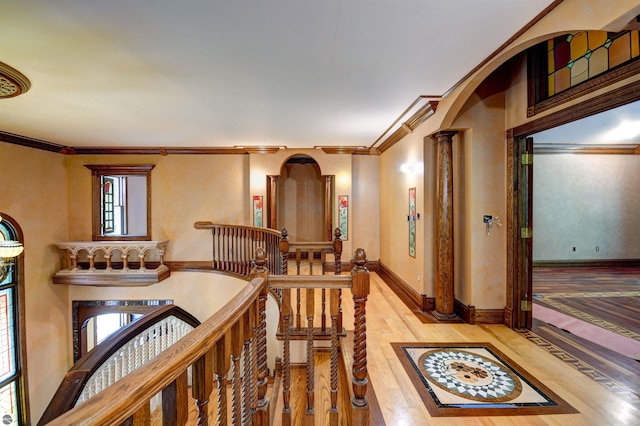 hallway featuring ornate columns, crown molding, and wood-type flooring