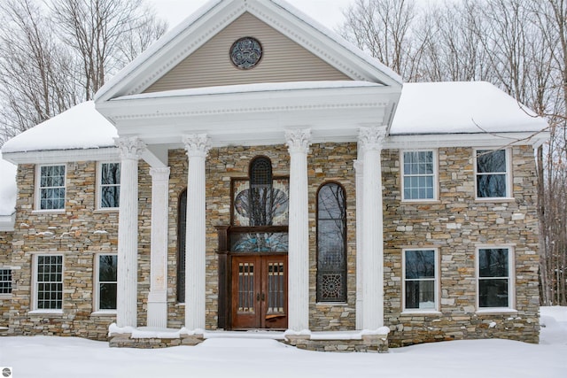 snow covered property entrance featuring french doors