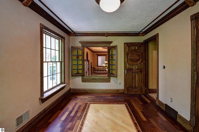 spare room with a textured ceiling, ornamental molding, and dark wood-type flooring