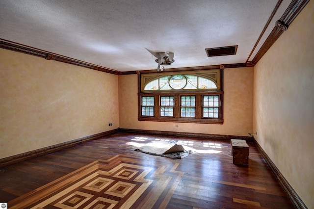 empty room featuring dark hardwood / wood-style flooring, a textured ceiling, and ornamental molding