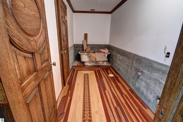 bathroom featuring a bath, hardwood / wood-style floors, tile walls, and crown molding