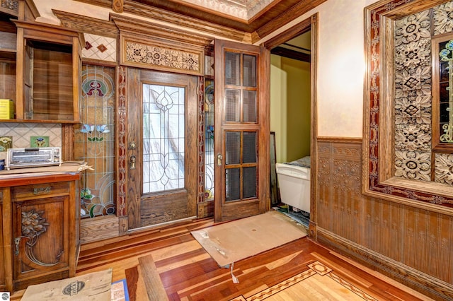 foyer entrance with crown molding and wood-type flooring