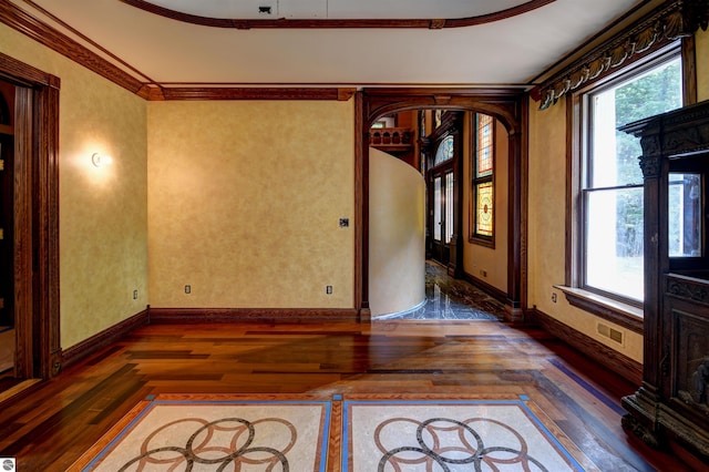 spare room with dark hardwood / wood-style floors, crown molding, and a wealth of natural light