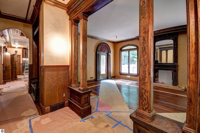 entrance foyer featuring wood-type flooring, crown molding, and decorative columns