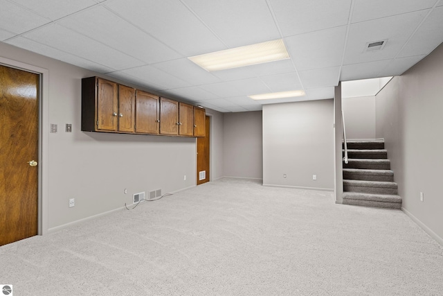 basement featuring a paneled ceiling and light colored carpet