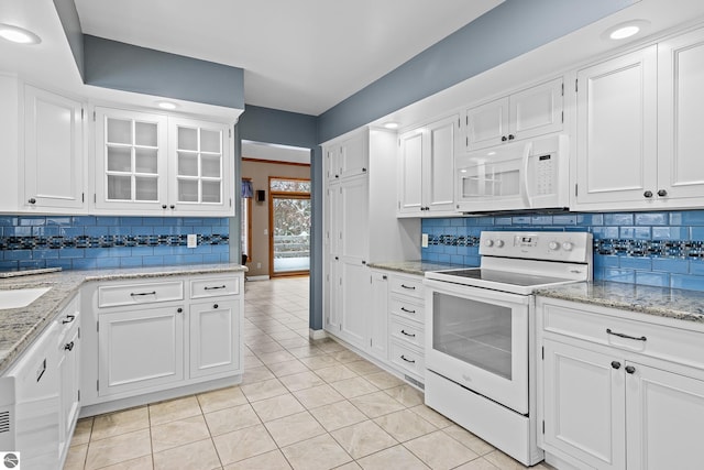 kitchen with decorative backsplash, white cabinetry, light tile patterned floors, and white appliances