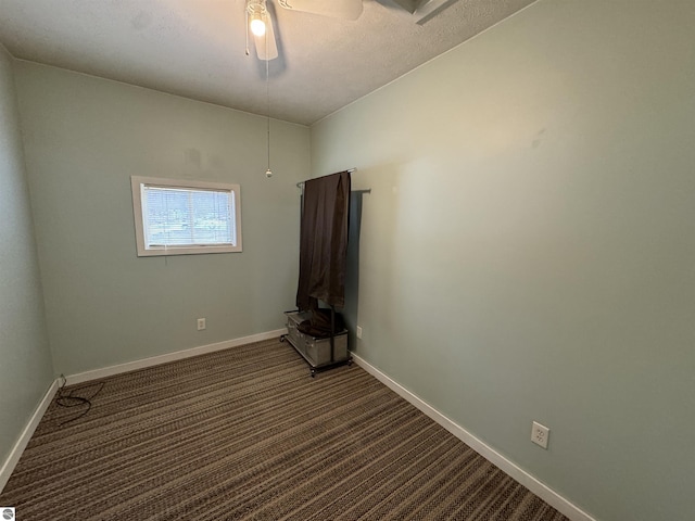 spare room featuring vaulted ceiling, dark carpet, and ceiling fan