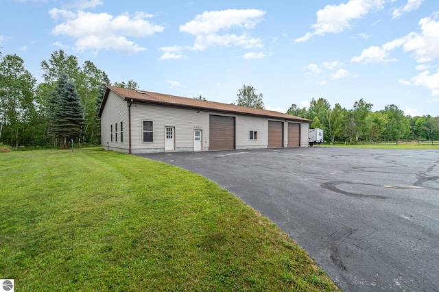 single story home featuring a front yard, an outbuilding, and a garage