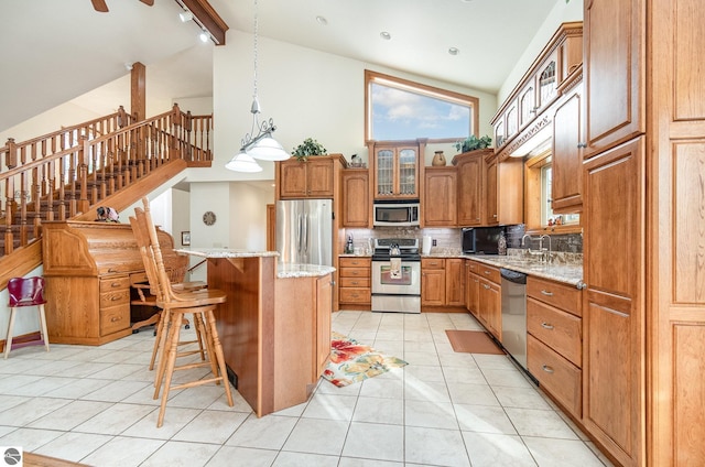 kitchen featuring a kitchen breakfast bar, stainless steel appliances, decorative light fixtures, high vaulted ceiling, and a center island