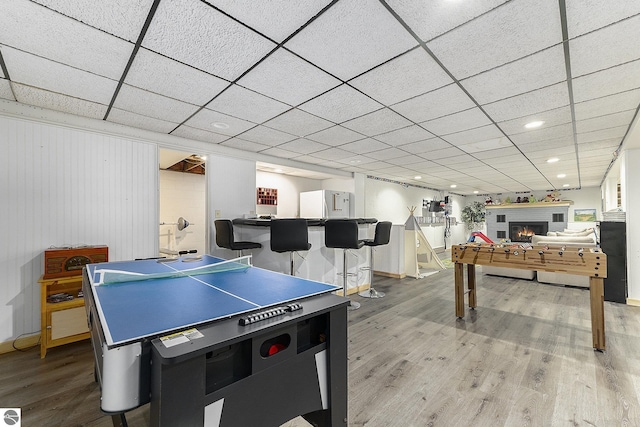 rec room with hardwood / wood-style flooring, a drop ceiling, and wood walls