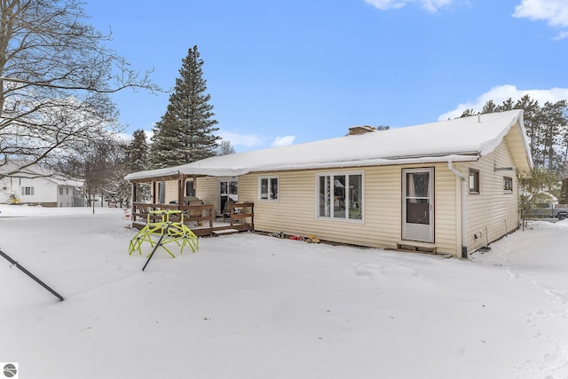 snow covered rear of property featuring a wooden deck