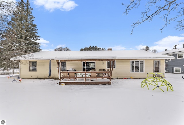 snow covered rear of property with a wooden deck