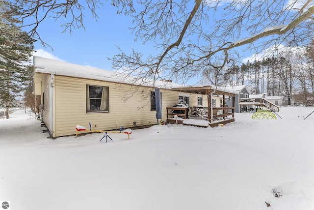 snow covered rear of property with a wooden deck