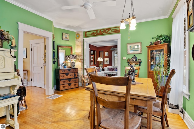 dining area with visible vents, a ceiling fan, crown molding, baseboards, and light wood-style flooring