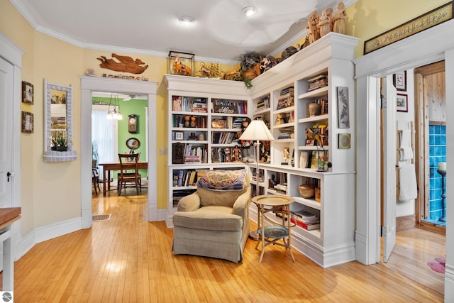 sitting room featuring hardwood / wood-style flooring, baseboards, ornamental molding, and visible vents