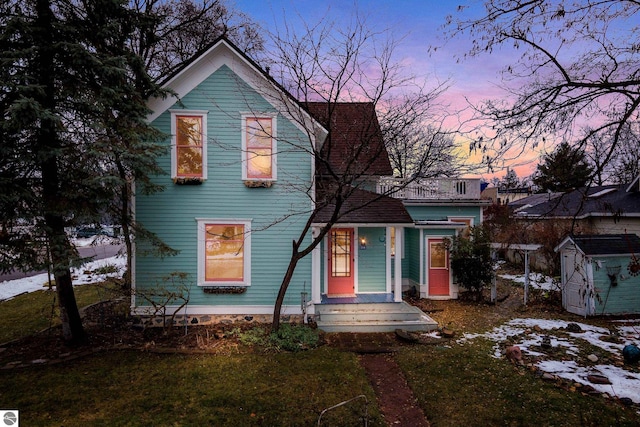 view of front of home featuring a lawn and a storage unit