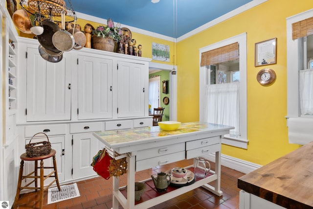 kitchen featuring a chandelier, crown molding, baseboards, and white cabinetry